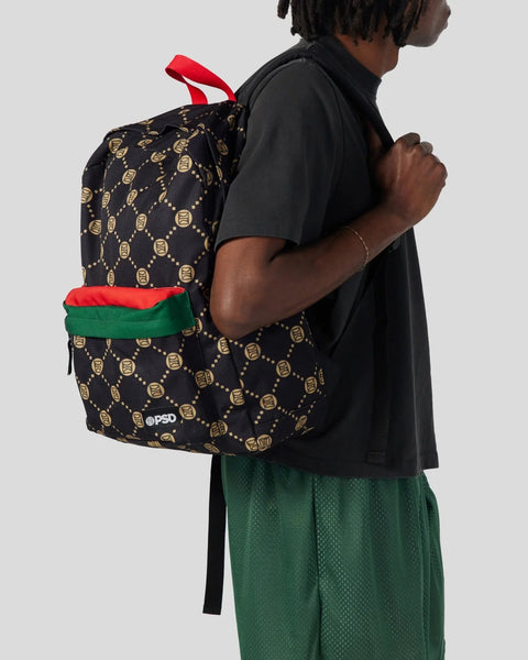 Black backpack with gold emblem pattern, red and green straps, worn by person in black shirt.