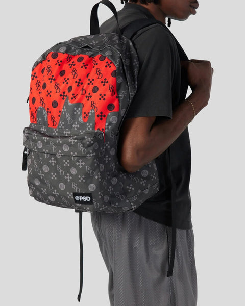 Black and red backpack with money symbol pattern worn by person in black shirt and gray pants.