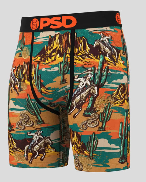 PSD boxer briefs with desert western print featuring cowboys, cacti, rock formations, and snakes in orange, teal, and yellow.