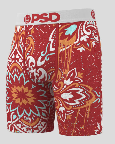 Red shorts with ornate floral and geometric pattern in white, gold, and turquoise with white PSD waistband.