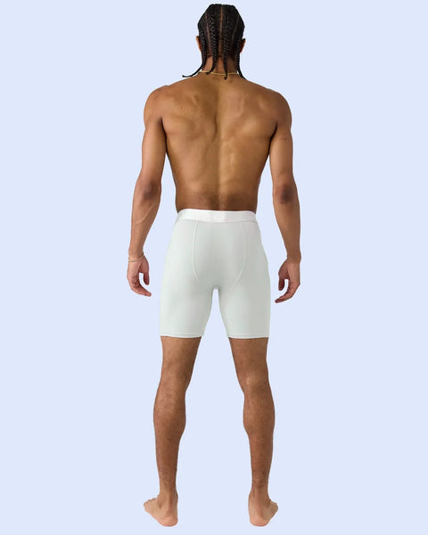 Man wearing white modal shorts, shown from behind against light blue background.