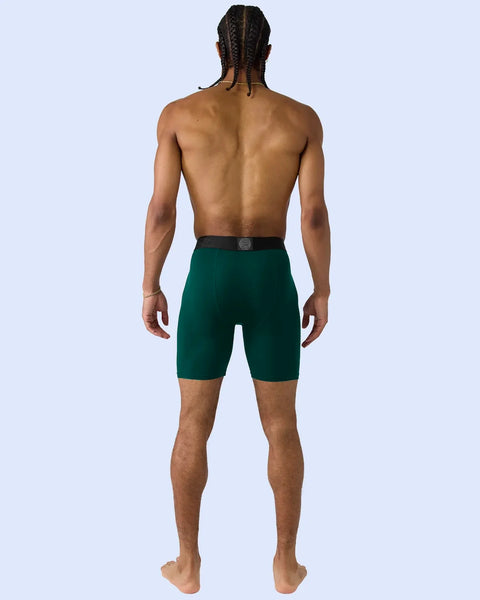 Man wearing deep green modal shorts with black waistband, back view.