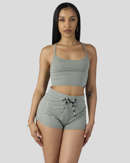 Woman wearing sage green cami crop top and matching shorts with drawstring waist.