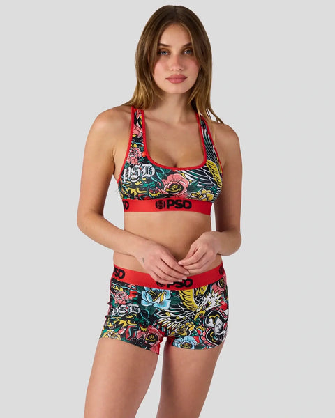 Woman wearing red sports bra and matching shorts with colorful floral and winged graphic print.