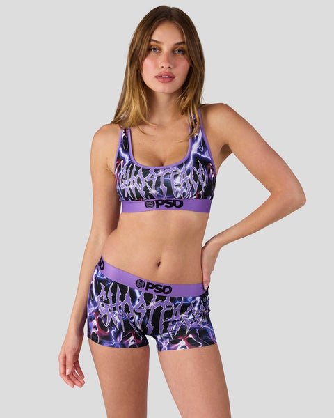 Woman wearing purple and black graphic sports bra and matching shorts with PSD branding.