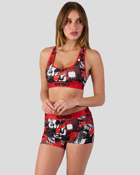 Woman wearing red and black checkered sports bra and matching shorts with red trim and logo band.