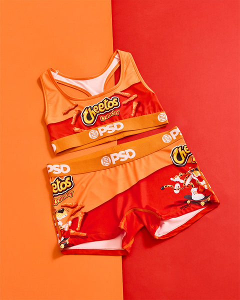 Cheetos Crunchy branded sports bra and shorts set in orange and red with PSD waistband on split color background.