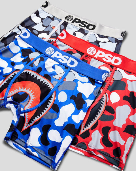 Three PSD brand underwear in blue, red, and gray with camouflage and graphic monster face designs.