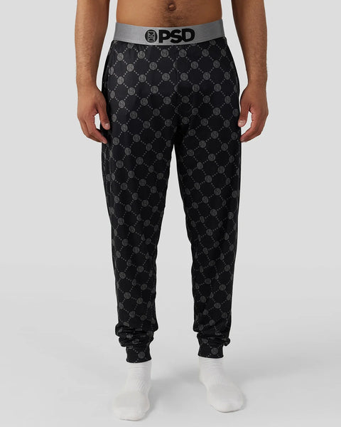Black lounge pants with gray repeating logo pattern and gray PSD waistband, shown with white socks.