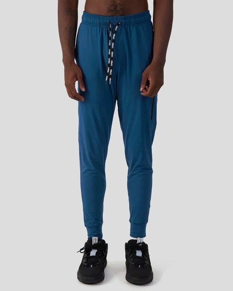 Deep teal joggers with drawstring waist and tapered ankles on a model.