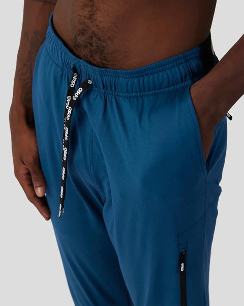 Deep teal joggers with elastic waistband, drawstring closure, and side pockets on model.