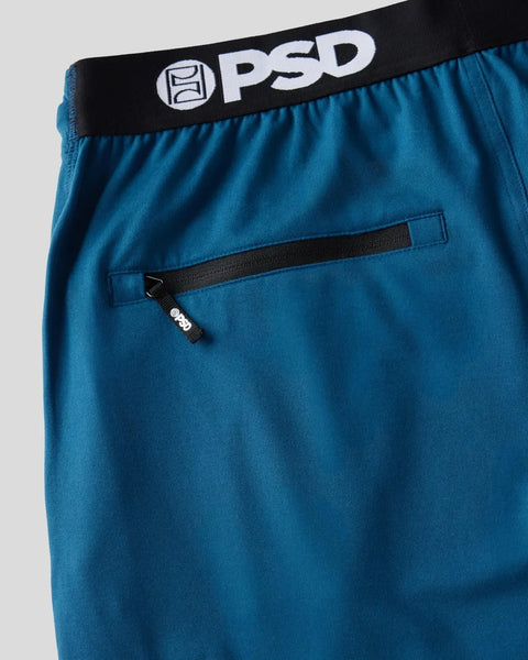 Deep teal joggers with black PSD waistband and zippered front pocket detail.