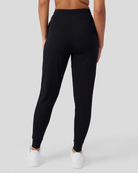 Black joggers with elastic waistband and tapered ankles, shown from back view on model wearing white sneakers.