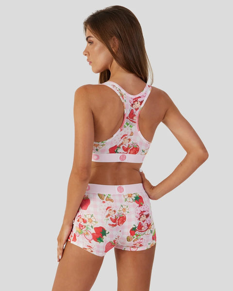 Woman wearing a two-piece loungewear set with strawberry and floral print on pink background, shown from back view.