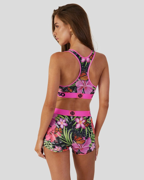 Woman wearing pink sports bra and shorts with black floral and butterfly print pattern.