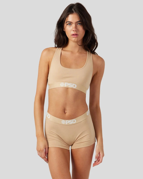 Sand-colored racerback sports bra and shorts set with logo waistband on model.