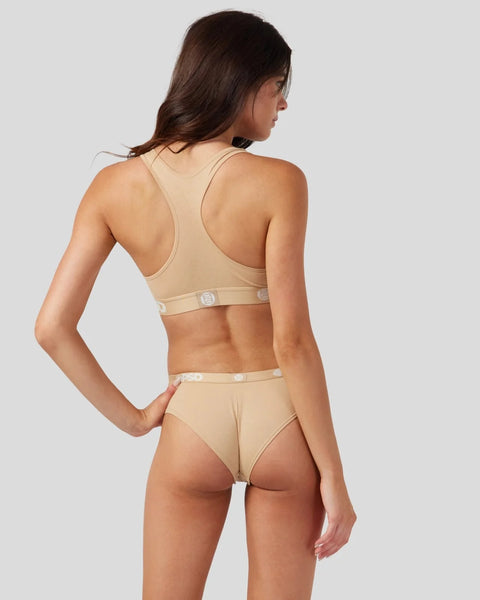 Woman wearing sand-colored modal sports bra and matching briefs with button details, shown from back.