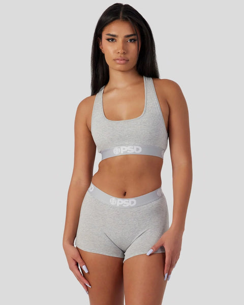 Woman wearing athletic grey racerback sports bra and matching shorts with branded waistband.