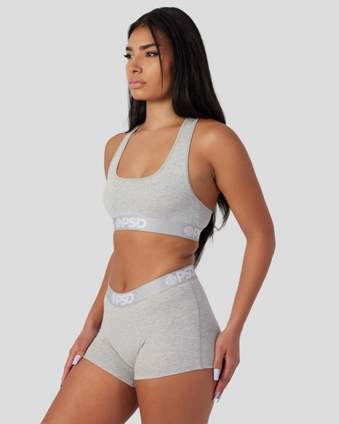 Woman wearing athletic grey racerback sports bra and matching shorts with branded waistband.