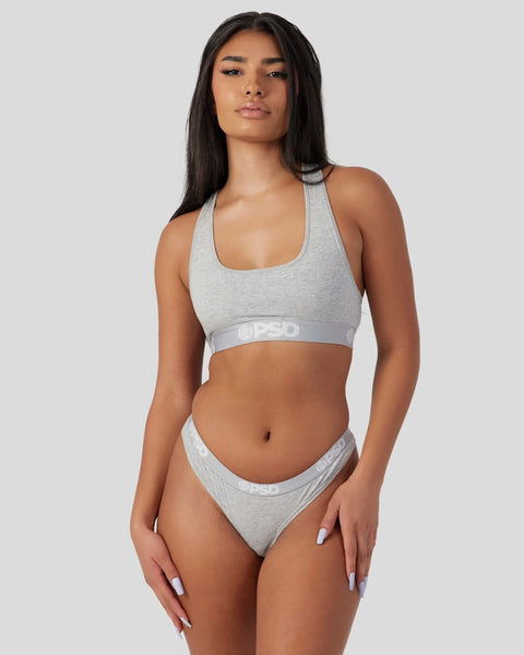 Woman wearing athletic grey racerback sports bra and matching bikini briefs with waistband branding.