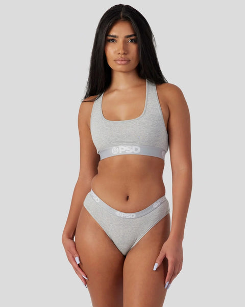 Woman wearing light grey racerback sports bra and matching briefs with branded waistband.