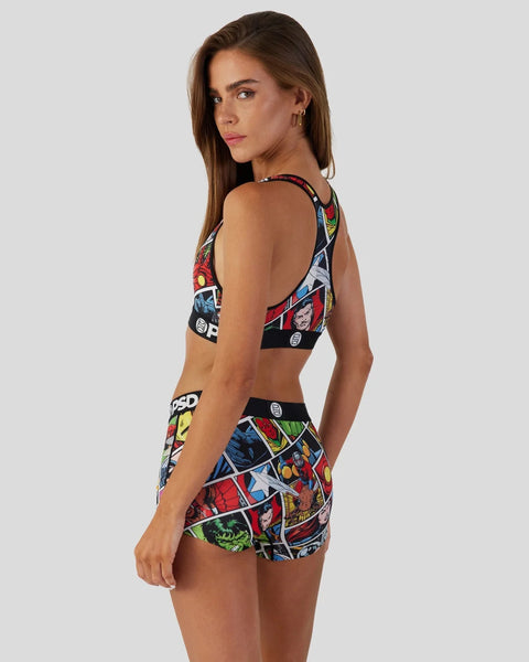 Woman wearing Marvel comic book print sports bra and shorts set with colorful superhero graphics on black background.