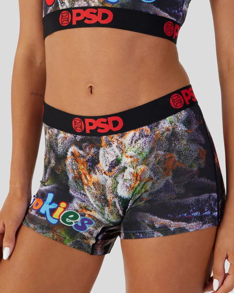 PSD brand shorts with colorful floral and textured print, black waistband with red logo, worn with matching sports bra.