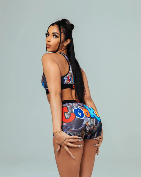 Woman wearing a colorful patterned sports bra and matching shorts with graphic print design.