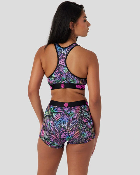 Woman wearing purple butterfly-patterned sports bra and shorts with pink accents, shown from back view.
