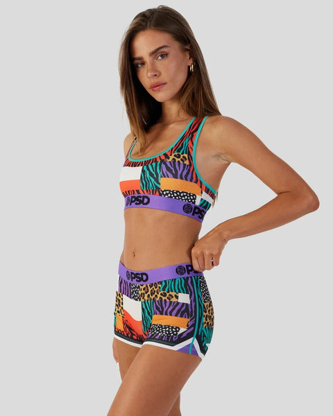 Woman wearing multicolored animal print sports bra and matching shorts with purple waistbands and PSD branding.