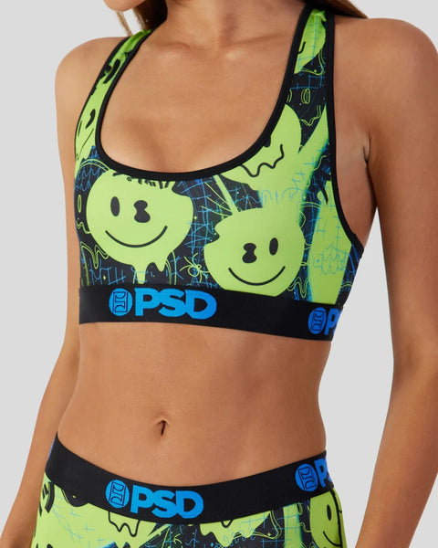 Neon yellow sports bra with black racerback straps, smiley face graphics, and blue PSD branding on dark patterned background.