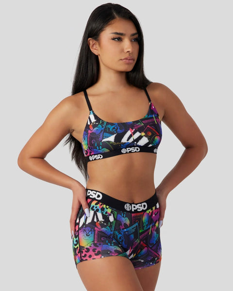 Woman wearing colorful Looney Tunes-patterned sports bra and shorts with PSD branding.