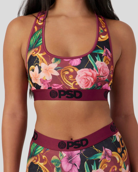 Racerback sports bra with floral and ornamental print in plum, pink, and gold tones with branded elastic band.