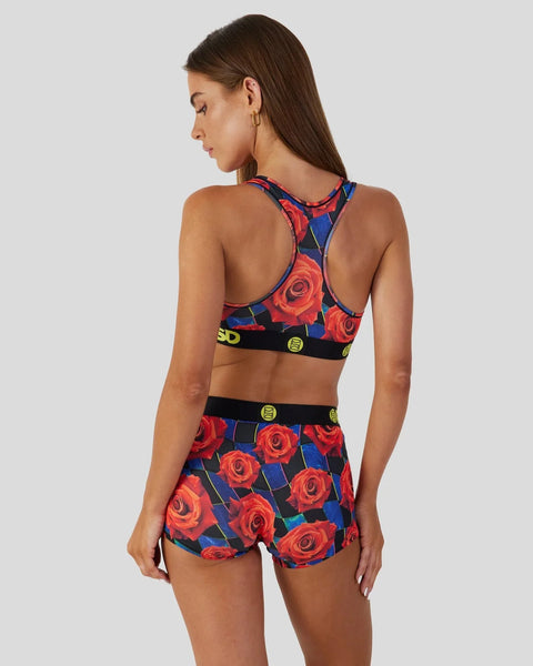 Woman wearing red floral sports bra and matching shorts with navy blue and black details, shown from back view.