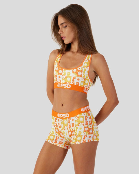 Woman wearing orange and yellow checkerboard pattern sports bra and shorts with PSD branding.