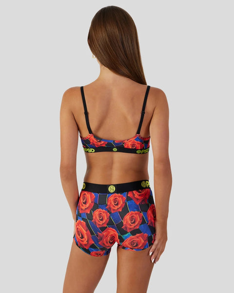 Women's two-piece swimsuit with red rose print on blue background and black straps and waistband.