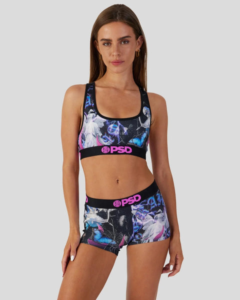 Woman wearing black, blue, and pink abstract patterned sports bra and matching shorts set with PSD branding.