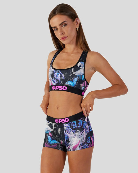 Woman wearing black sports bra and shorts with blue butterfly and pink graffiti print and PSD branding.