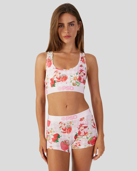 Woman wearing white sports bra and shorts with red strawberry and floral print throughout.