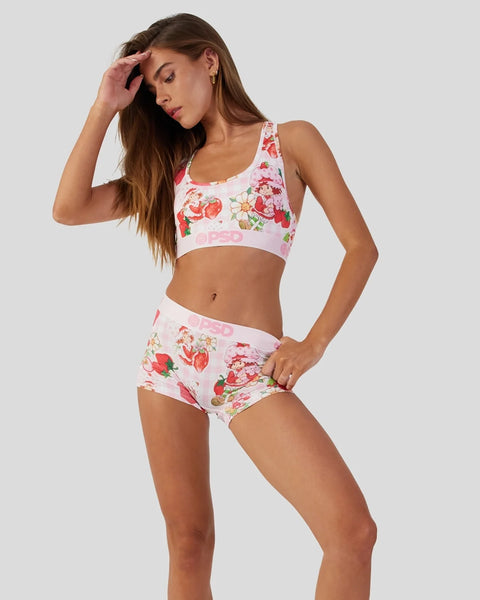 Woman wearing strawberry and floral print sports bra and matching shorts set in pink and white.