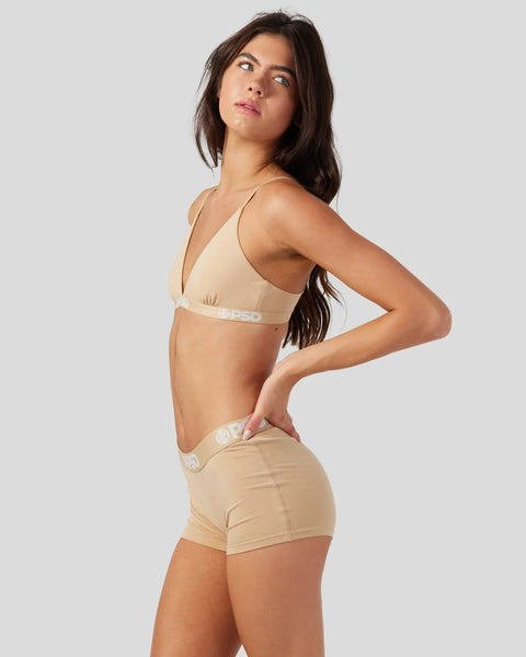 Woman wearing sand-colored modal bra and matching shorts with white waistband branding.