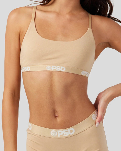 Woman wearing a sand-colored bra with thin straps and matching low-rise briefs with visible PSD branding.