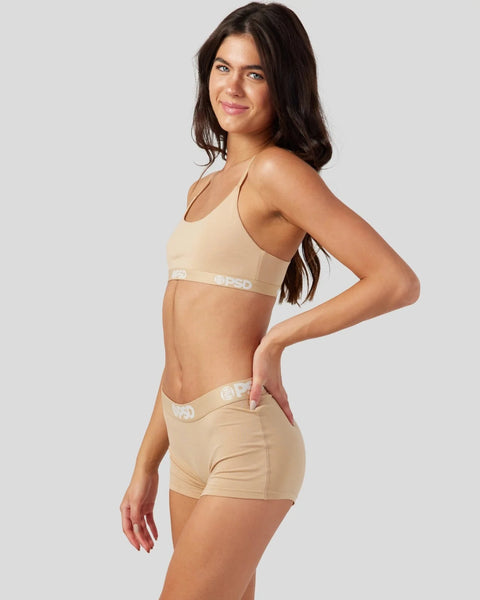 Woman wearing sand-colored modal bra and shorts with branded waistband.
