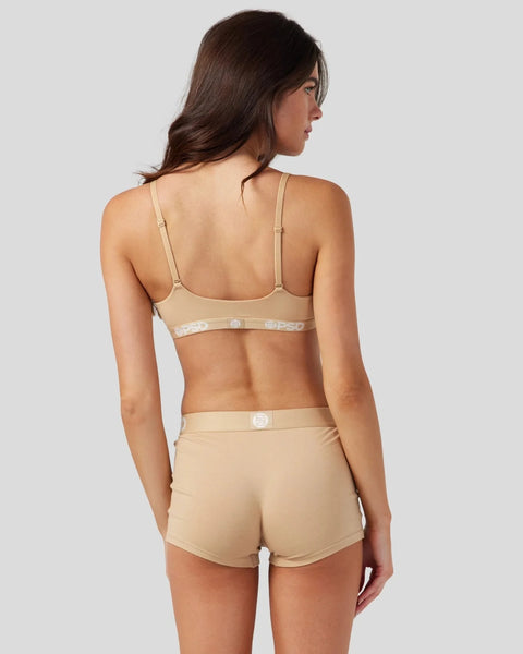Woman wearing sand-colored bra and matching shorts with logo detailing, shown from back view.