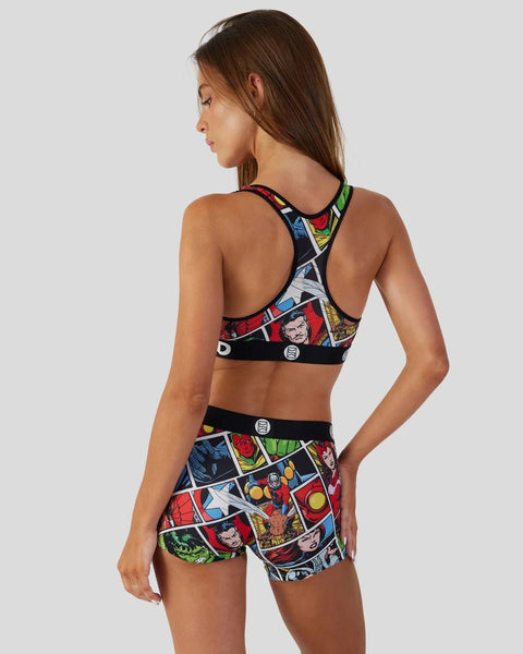 Woman wearing Marvel comic-print sports bra and shorts set with colorful panel designs and black trim.