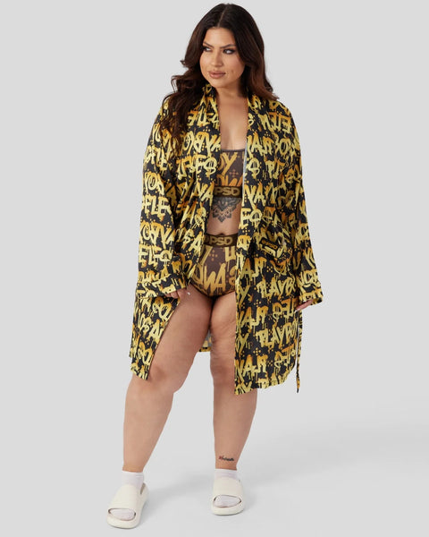 Woman wearing black and yellow Playboy graffiti print robe, matching crop top and shorts set with white slide sandals.