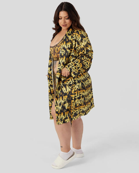 Woman wearing black and yellow graffiti print button-up shirt with matching shorts and white socks.