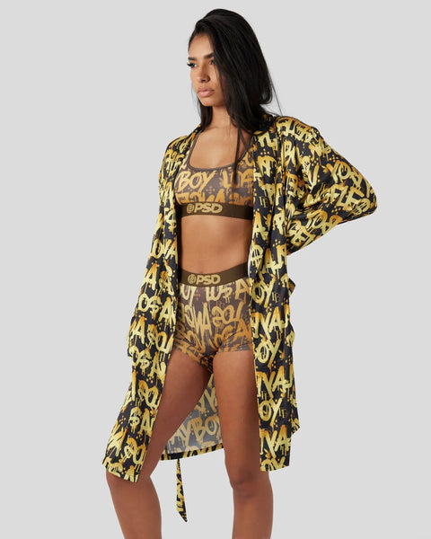 Woman wearing black and gold graffiti print cardigan, sports bra, and shorts with matching pattern and branding.