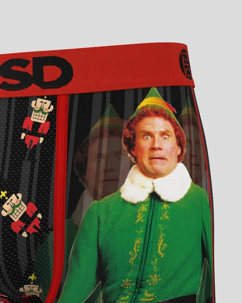 Person wearing green elf costume with white collar and red knit hat visible through packaging window.