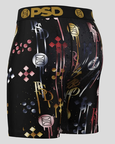 Black PSD shorts with gold, pink, and navy abstract geometric print and repeated branding.